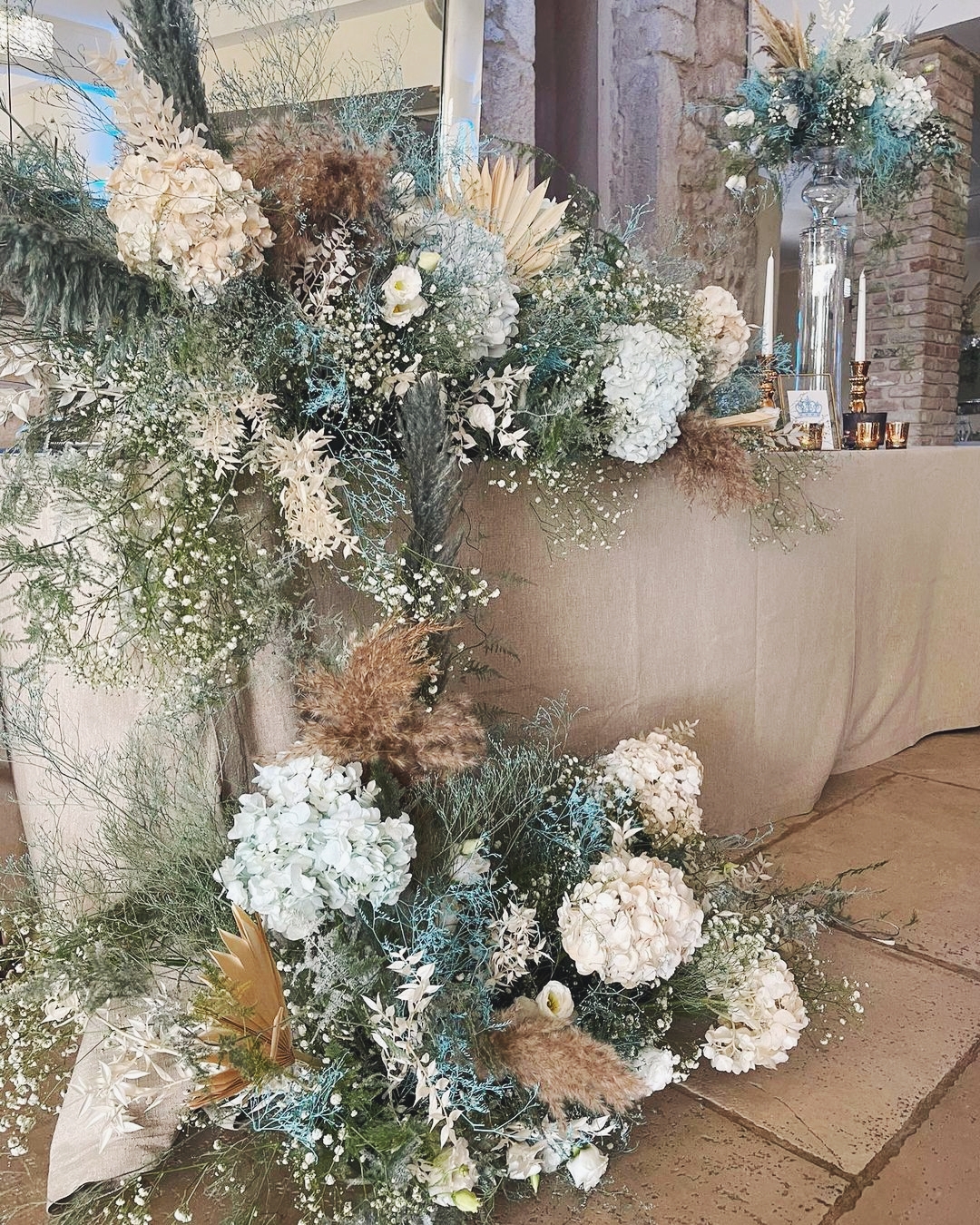 Composizione floreale con ortensie bianche, azzurre e pampas caramello per battesimo bimbo