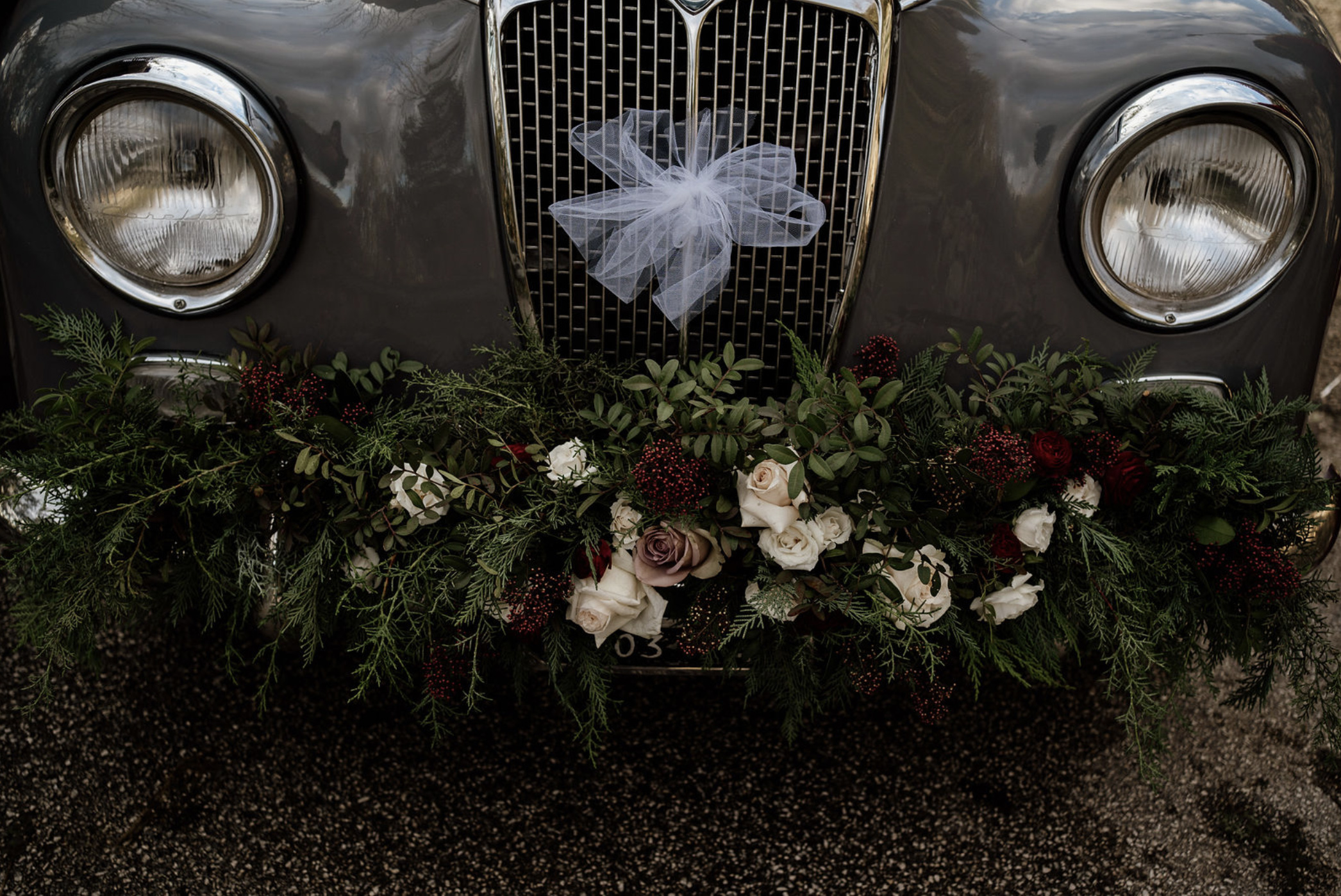 Decorazione floreale auto sposa per matrimonio in inverno, con verdi di stagione, rose e bacche rosse