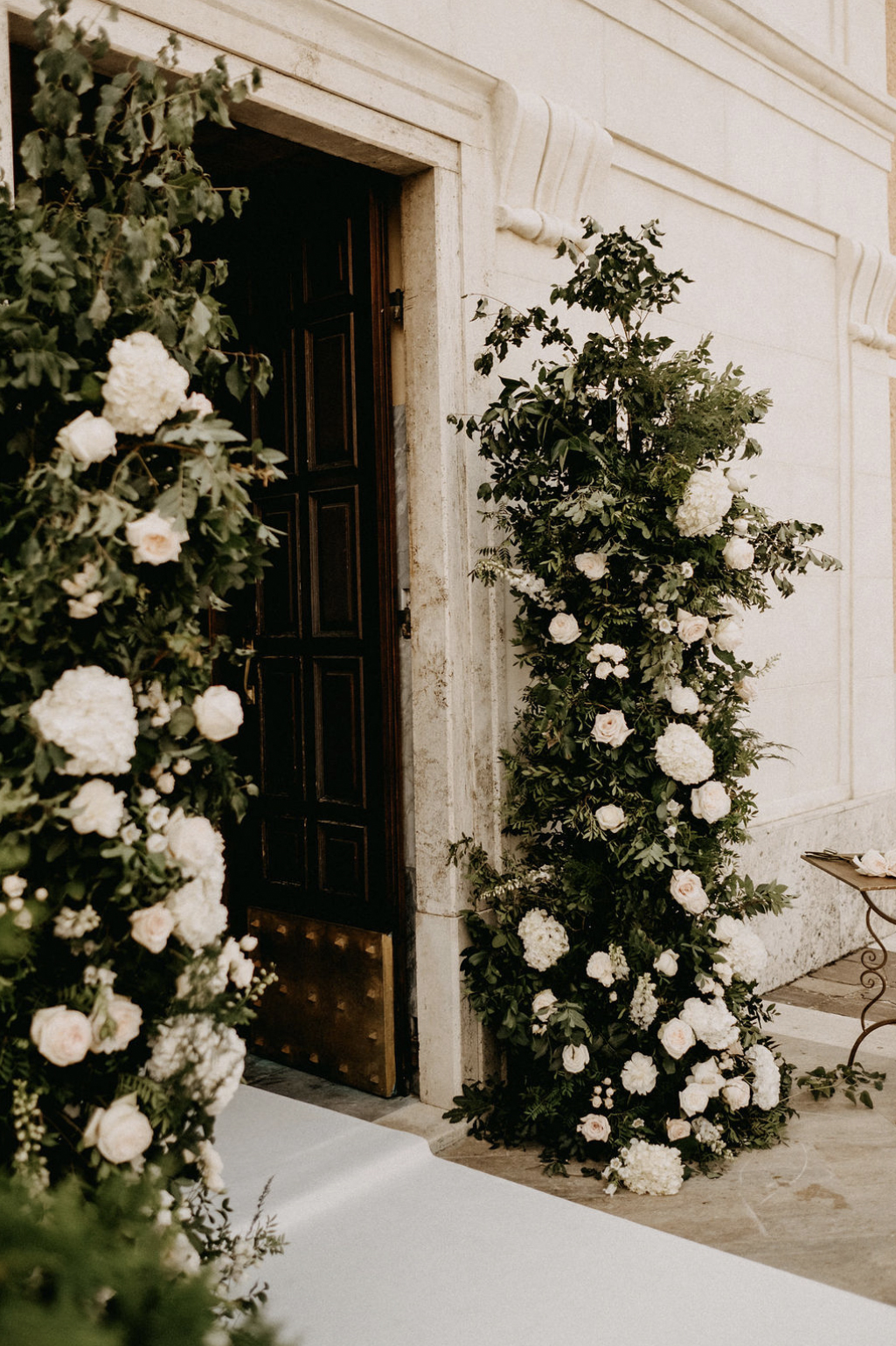 Addobbo ingresso chiesa in stile botanico con verdi di stagione e fiori bianchi