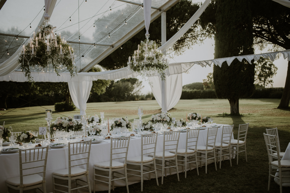 Tavolo lungo per ricevimento di matrimonio all'aperto, con addobbo floreale bianco e verde