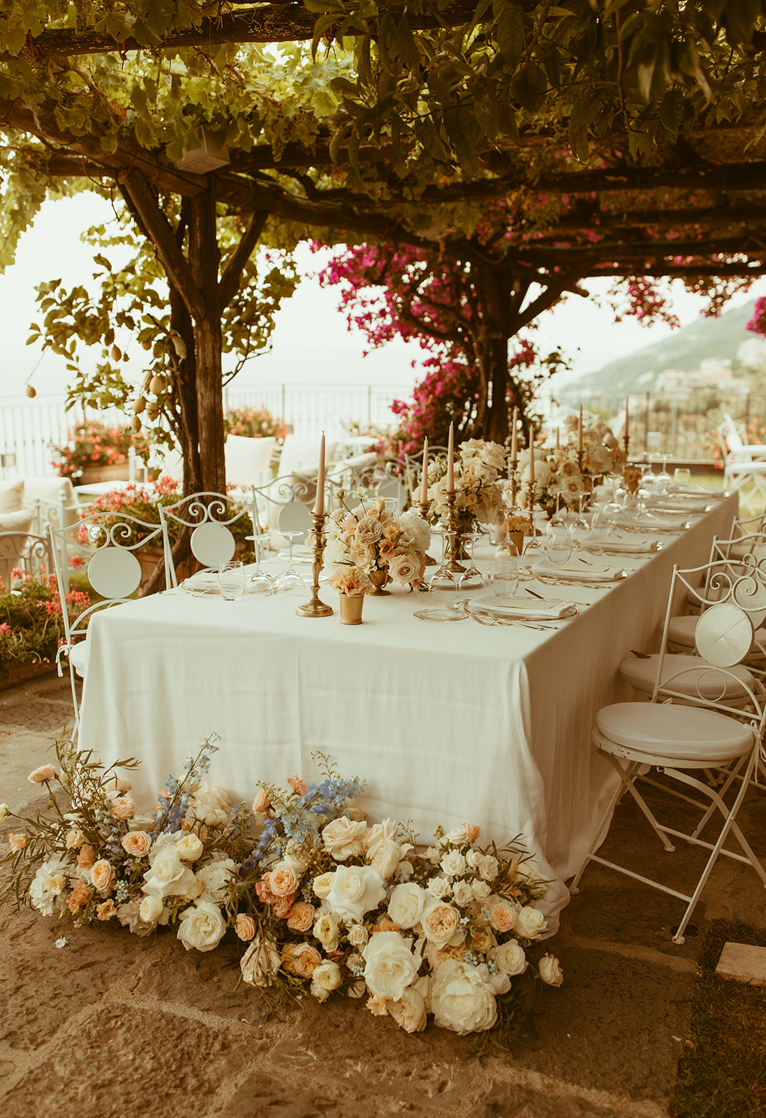 Allestimento floreale per tavolo lungo con candele e fiori bianchi, rosa e celesti