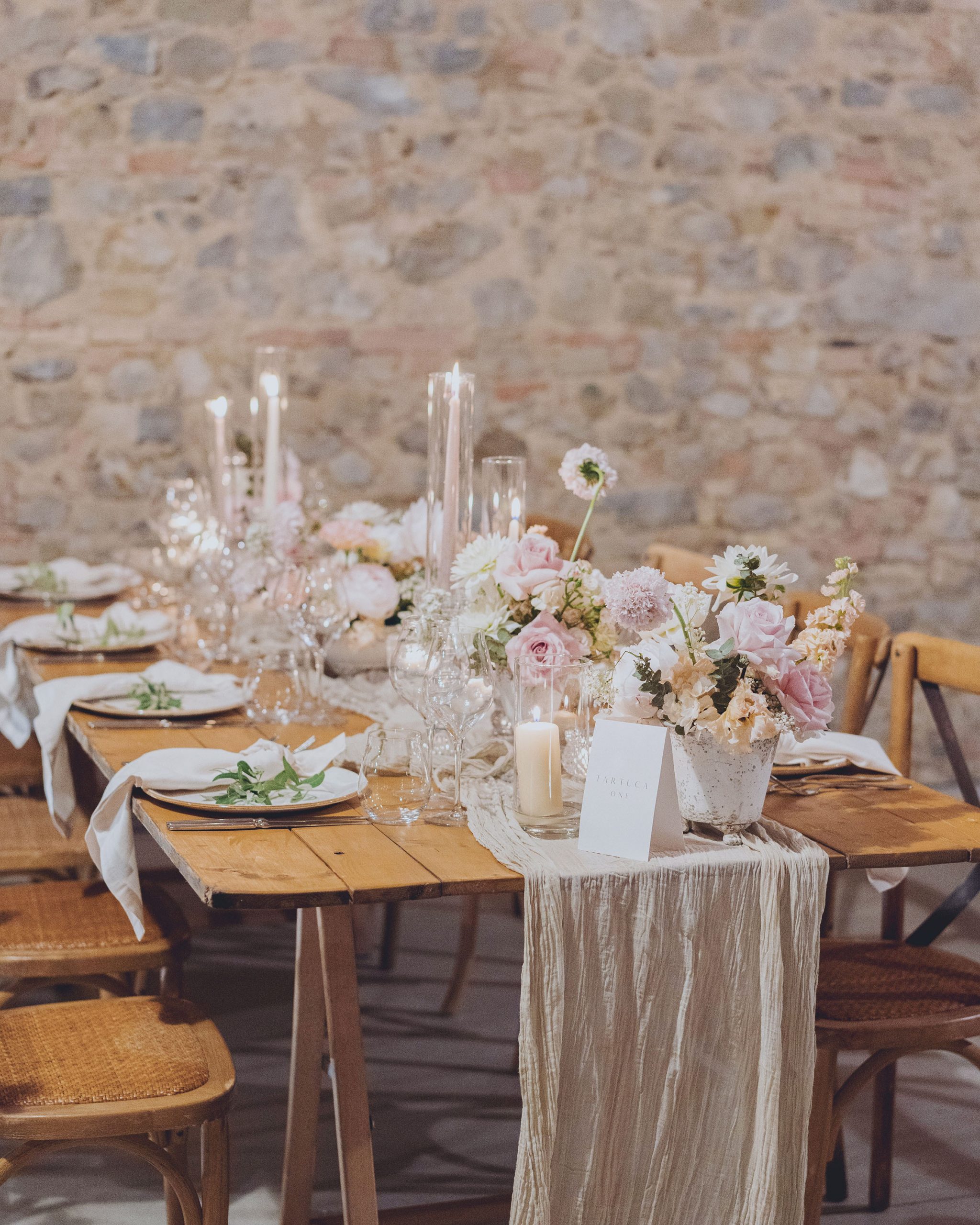 Allestimento tavolo con piccole composizioni floreali e candele coniche per ricevimento nuziale in Toscana