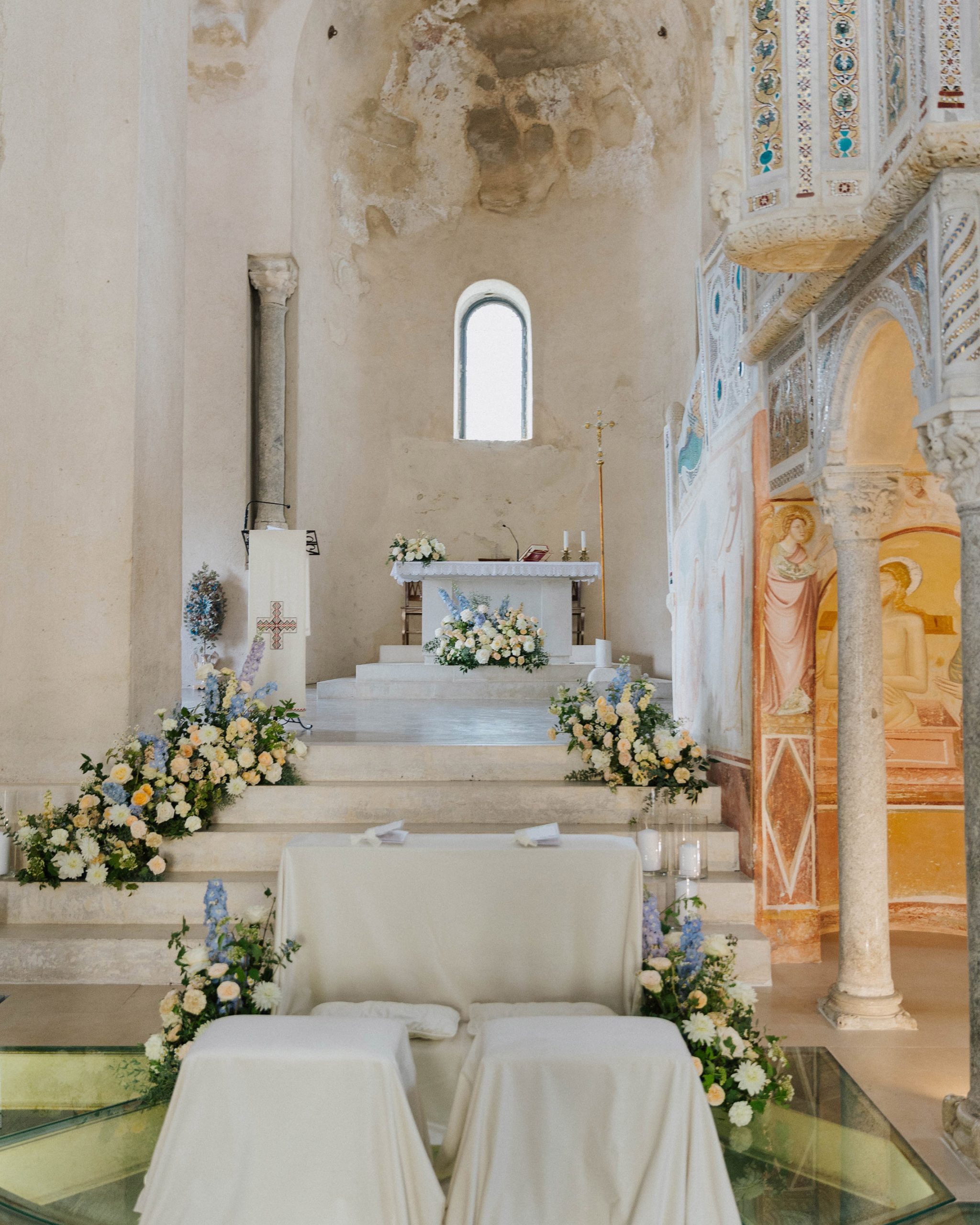 Interno chiesa con composizioni floreali nei toni del giallo, bianco e celeste polvere